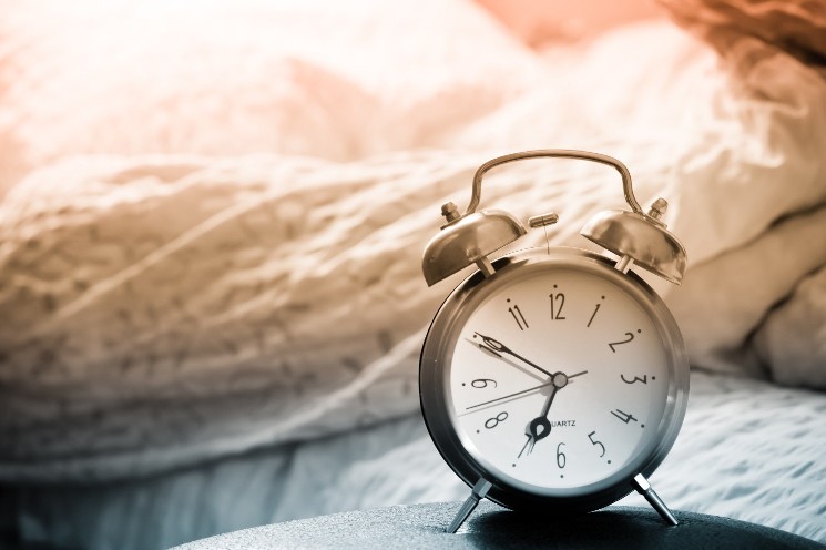 clock and bed showing wake time in bedroom